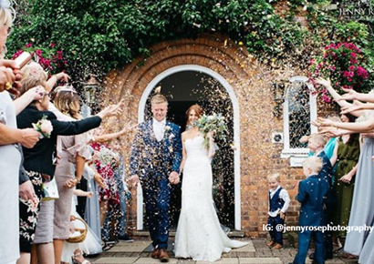 Newly married couple having confetti thrown over them by the wedding guests as they exit their ceremony