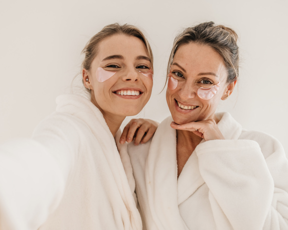 Happy Caucasian Women Use Eye Patches Wear Bathrobes Look Camera White Background Concept Preserving Youth